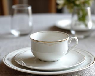 Elegantes, weißes Porzellan-Geschirrset mit goldenen Akzenten auf einem schön gedeckten Tisch